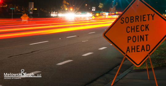 sobriety checkpoint ahead sign on road at night