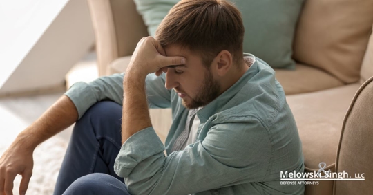 man sitting on floor upset with hand on forehead