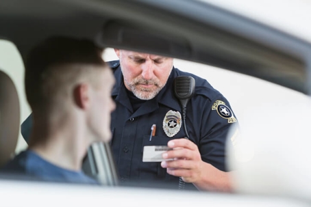 policeman inspects drivers license during traffic stop