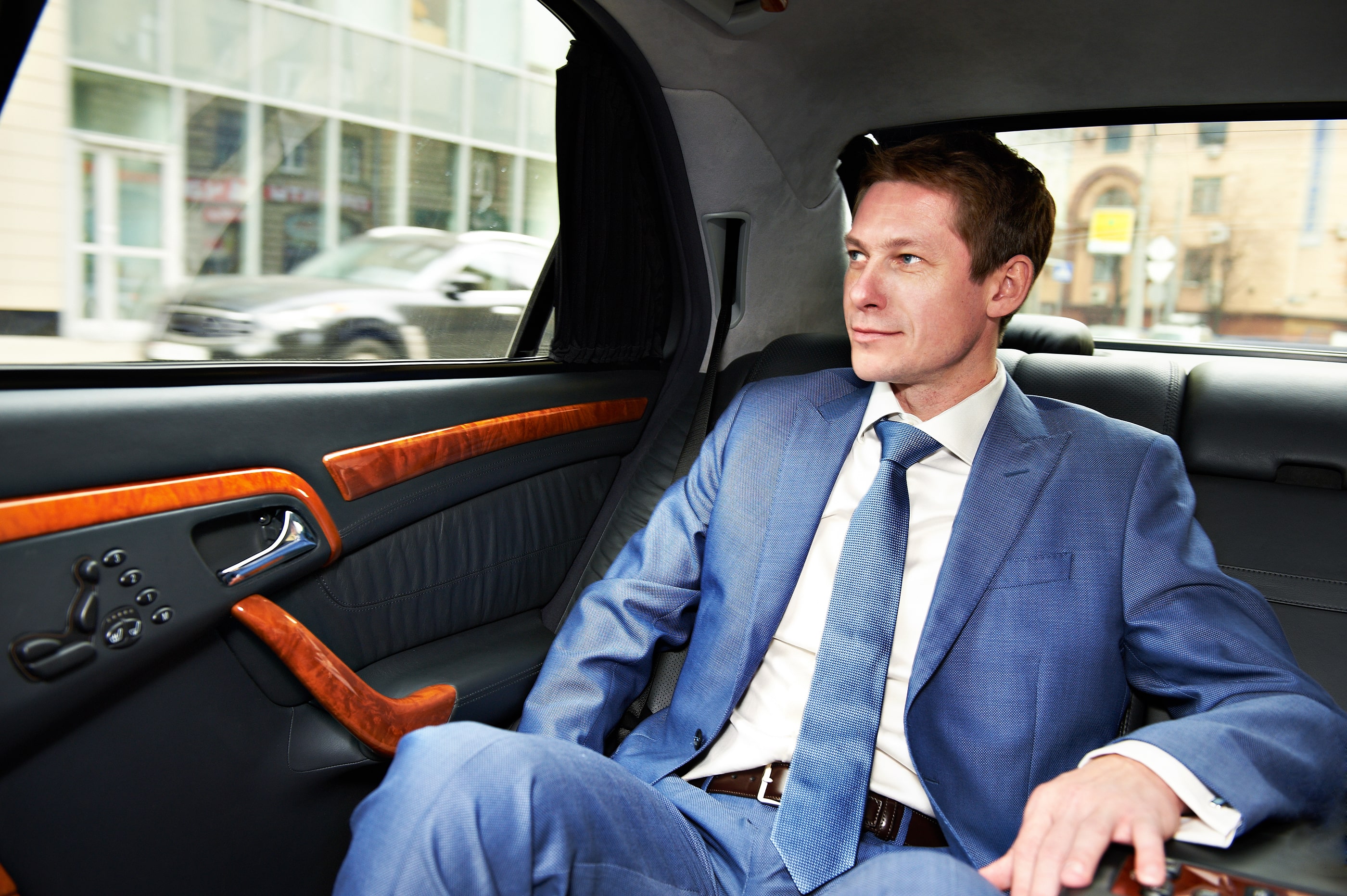 Man wearing blue suit sitting in car